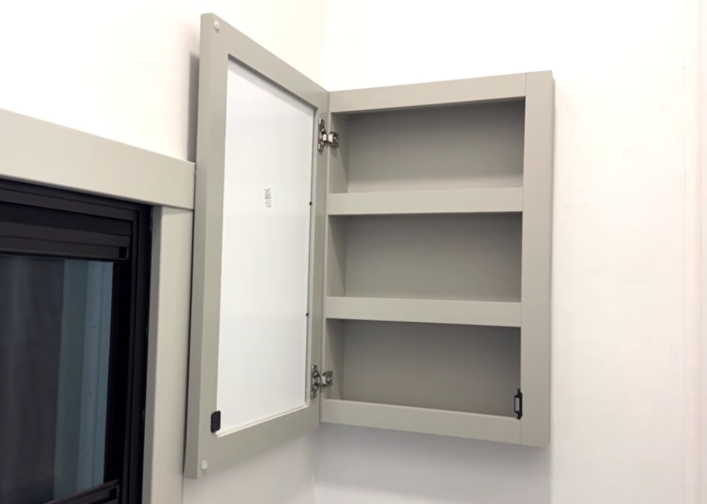 RV bathroom wall cabinet with open door and three interior shelves