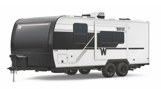 Winnebago Thrive travel trailer with slide-out and dual axles displayed on a white background.