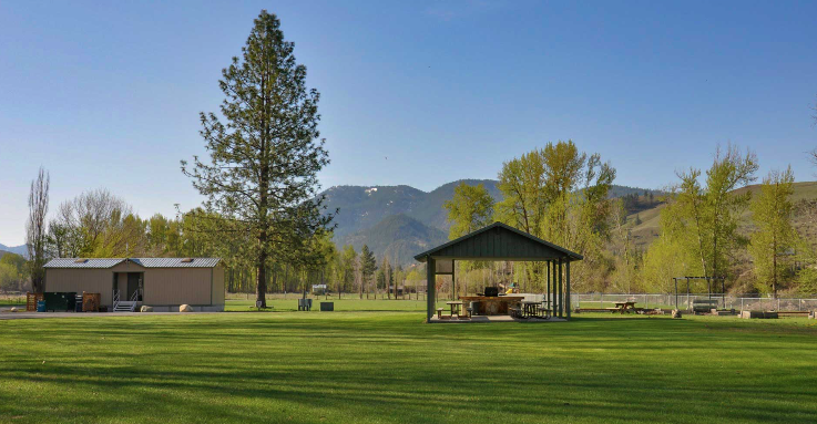 Spacious grassy dog park area at pet-friendly RV campground with pavilion and mountain views