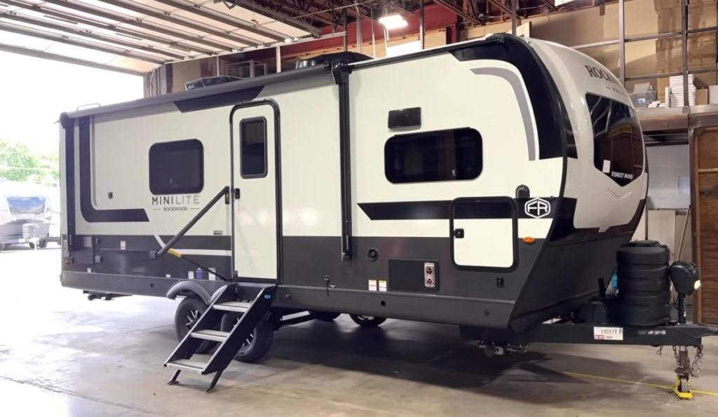 Rockwood Mini Lite travel trailer by Forest River displayed indoors with entry steps and awning.