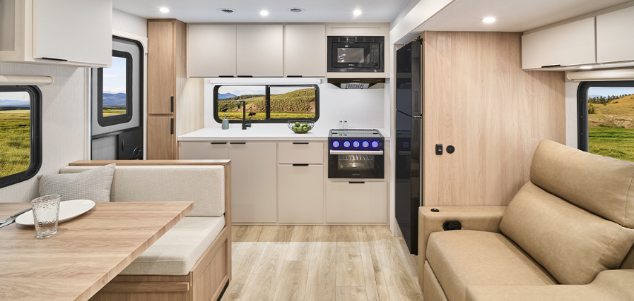 Modern Winnebago Thrive travel trailer interior with kitchen, booth dinette, sofa seating, and large scenic windows.