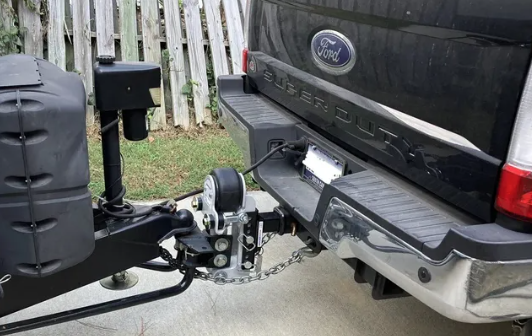 Pickup truck hitch setup with weight distribution system and trailer coupler attached for towing an RV.