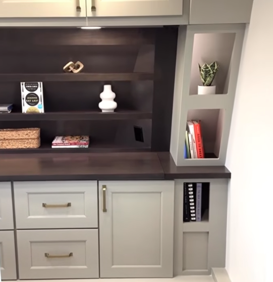 Built-in RV storage cabinet with shelves, drawers, and decorative display space in a modern travel trailer interior.