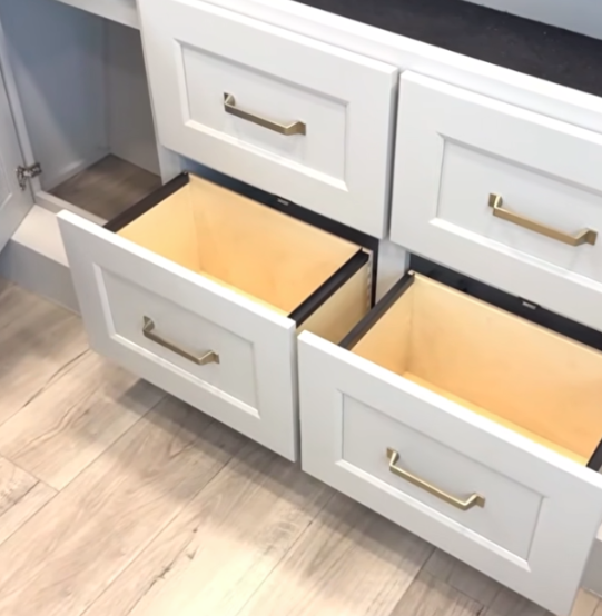 Travel trailer kitchen drawers pulled open showing storage space with soft-close cabinetry and modern hardware.