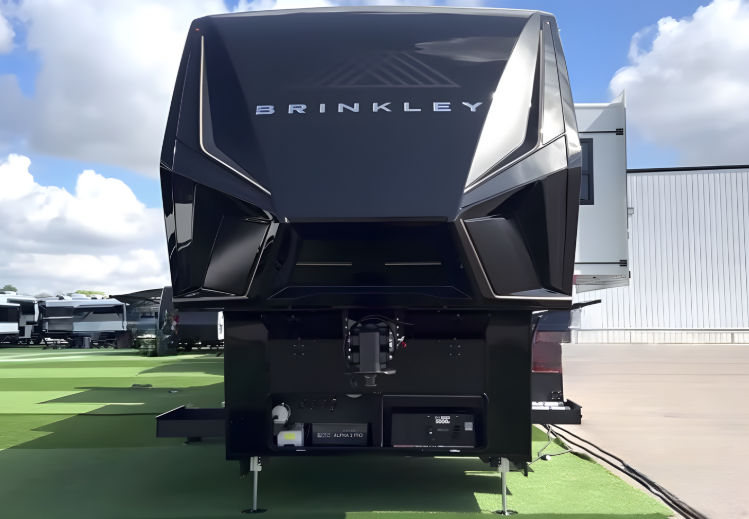 Front view of a Brinkley fifth wheel RV with aerodynamic nose design and hitch connection visible.