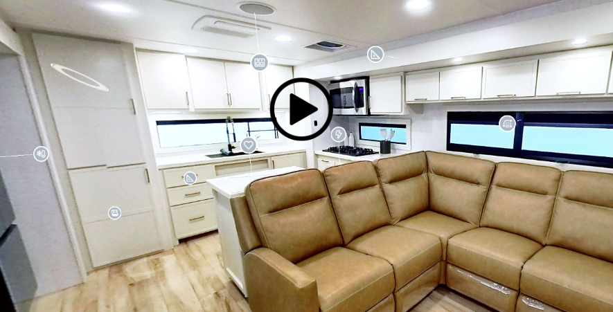 Spacious travel trailer interior with an L-shaped sectional sofa, kitchen island, and white cabinetry, shown with an interactive 3D tour overlay.