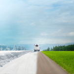RV driving down a road split between winter snow and green summer landscape, symbolizing seasonal travel.