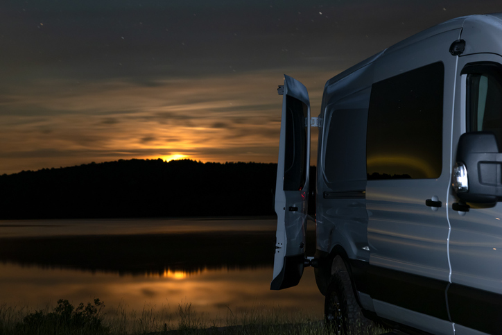 Van Life, Camper van Parked Close to a lake at Night During Summer, the Laurentian Mountains, Quebec, Canada. The moon is rising over the mountains.