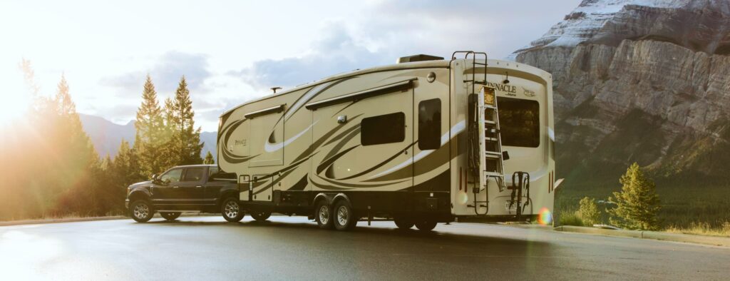 fifth wheel RV with travel access parked in a mountain setting, showcasing a towable camper ideal for road trips and frequent travel stops