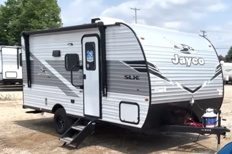 Jayco Jay Flight SLX travel trailer parked outdoors with entry steps down, front hitch setup, and gray-and-white exterior graphics.