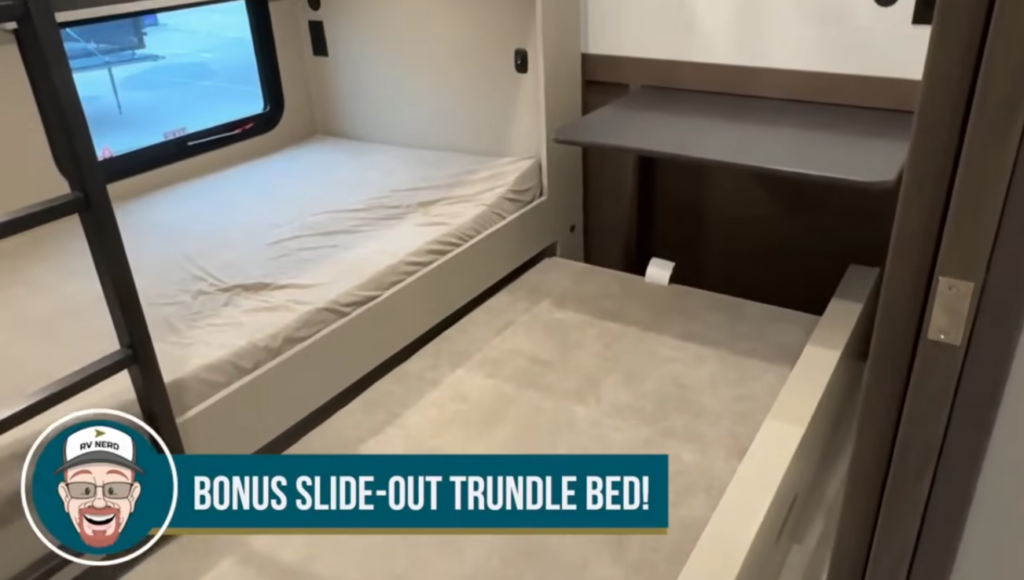Travel trailer bunk room with a single bunk bed, ladder access, and a slide-out trundle bed below, with text overlay reading “Bonus slide-out trundle bed!