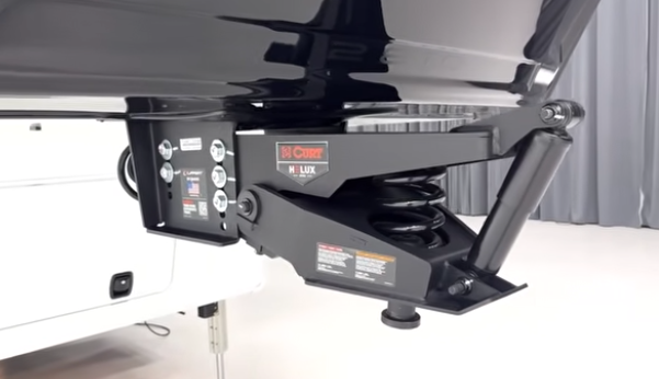 Close-up of fifth wheel hitch system with Curt Helux air ride pin box and suspension components mounted beneath the RV front cap