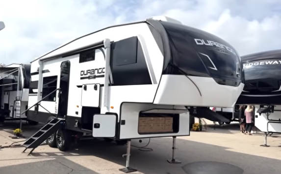 Durango fifth wheel RV on display outdoors with front hitch raised, entry steps extended, and exterior storage compartments visible.