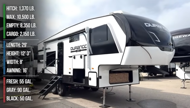 Durango fifth wheel RV on display outdoors with specifications listed on the left, including weight, dimensions, and tank capacities, and entry steps extended.