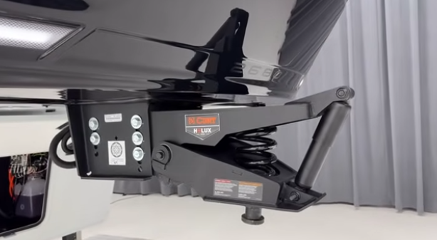 Close-up of fifth wheel hitch system showing CURT Helux suspension with shock absorber and mounting hardware beneath the RV.