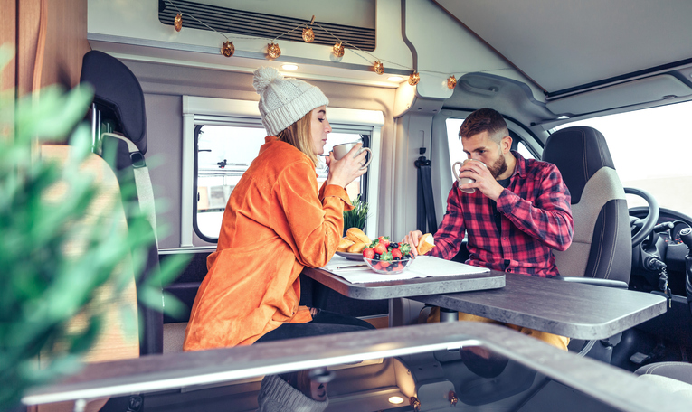 Friends having breakfast in a camper van in the morning