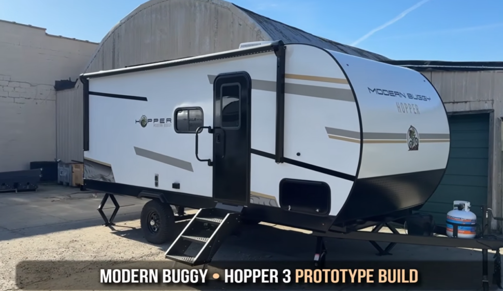 Modern Buggy Hopper travel trailer prototype featuring a sleek aerodynamic profile, compact lightweight construction, off-road tires, and a large power awning. Designed for adventure-focused travelers, the Hopper combines easy towing, modern styling, and versatile camping features in a compact RV built for weekend getaways and off-grid exploration