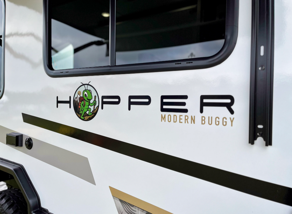 Close-up exterior view of the Modern Buggy Hopper travel trailer showcasing the distinctive Hopper branding and mascot logo on the sidewall.