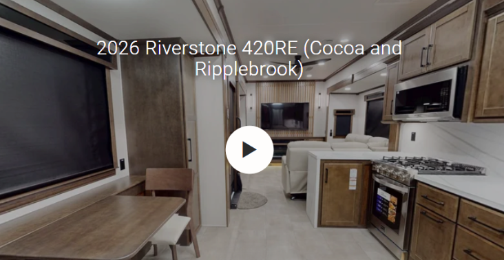 Interior of the 2026 Forest River RiverStone 420RE luxury fifth wheel featuring a residential kitchen with solid-surface countertops, premium gas range, stainless steel appliances, freestanding dining table, theater seating, entertainment center, and rich Cocoa and Ripplebrook décor. Designed for full-time RV living, the spacious rear entertainment floorplan delivers residential comfort, luxury finishes, and an open-concept layout ideal for extended travel and camping.
