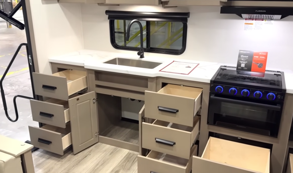 Residential-style RV kitchen with every drawer and cabinet open, highlighting the abundant storage available for cookware, utensils, pantry items, and kitchen essentials.