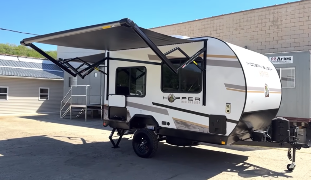 Exterior view of the Modern Buggy Hopper travel trailer with its large power awning extended, creating a comfortable outdoor living space.