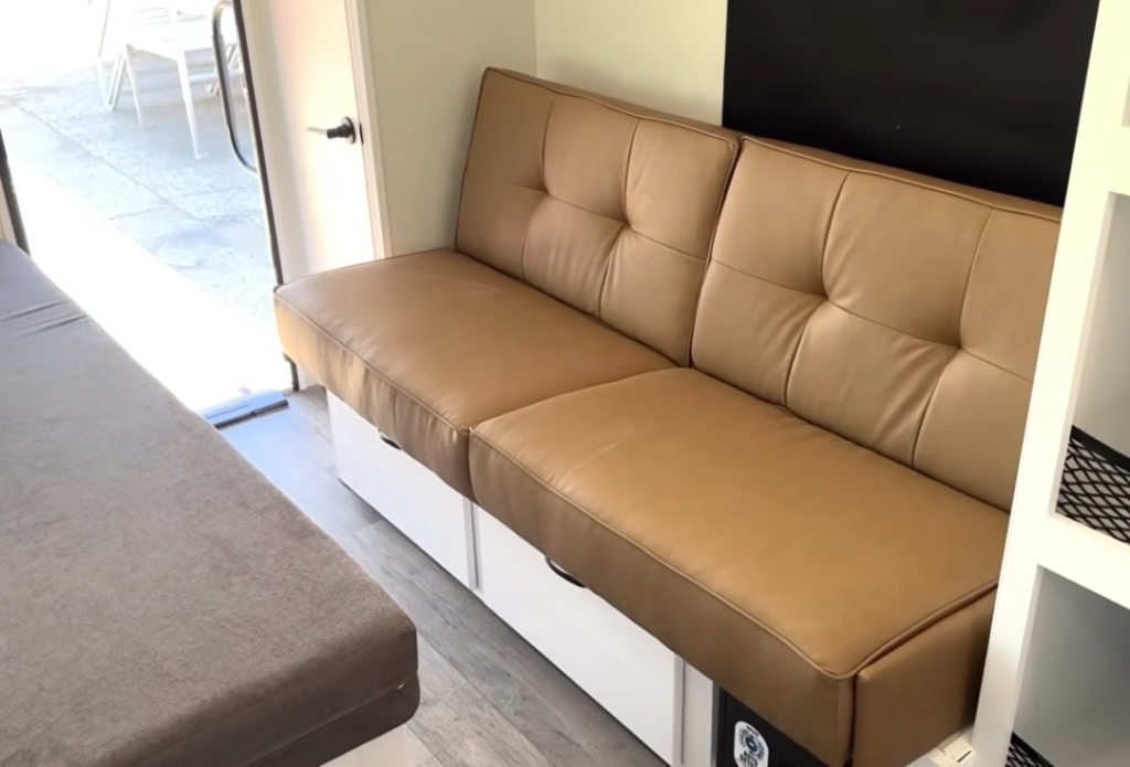 Comfortable jackknife sofa inside the Modern Buggy Hopper travel trailer featuring premium leather upholstery and hidden storage underneath.