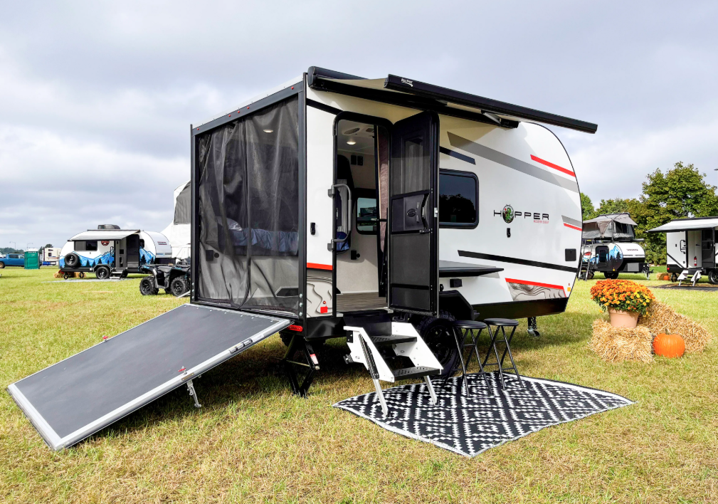 Rear view of the Modern Buggy Hopper travel trailer with the rear ramp door lowered to create a patio-style entrance.