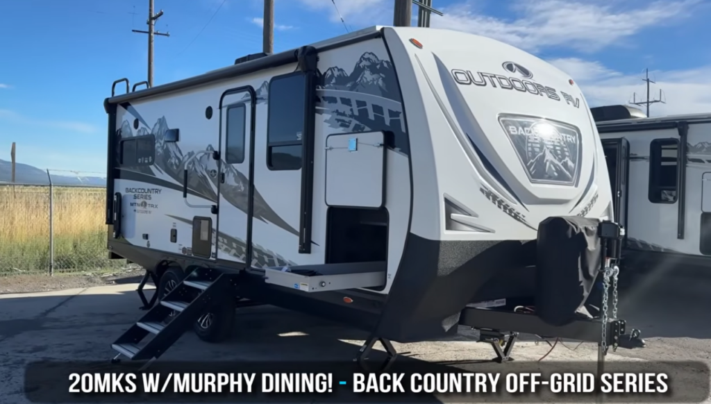 Front three-quarter view of the Outdoors RV Back Country Series 20MKS travel trailer featuring a Murphy bed floorplan, rugged mountain-inspired graphics, aluminum entry steps, and a durable fiberglass front cap.